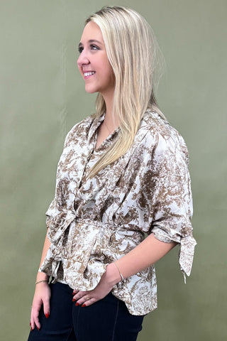 Woman wearing a patterned blouse against a plain background