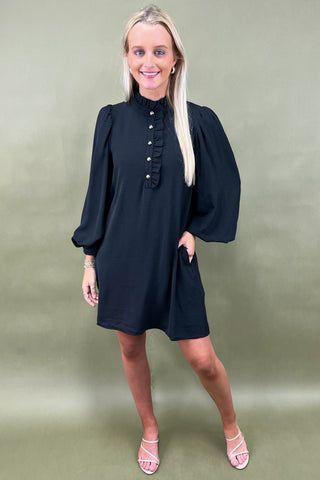 Woman wearing a black dress with balloon sleeves against a green background