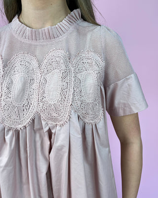 Pink dress with lace details on a pink background