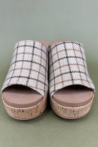 Pair of plaid patterned slides with cork sole on a green background