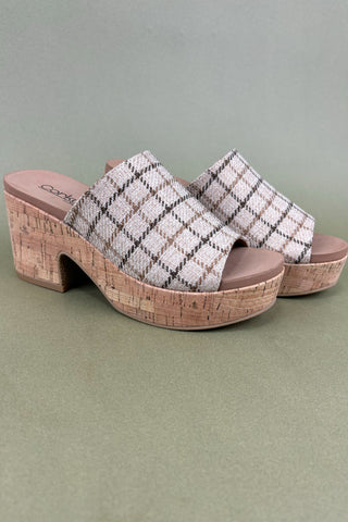 Pair of plaid clogs with cork soles on a green background