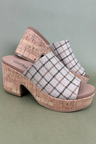 Woven clog sandals with cork platform on a green background