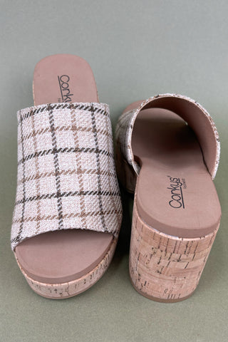 Pair of plaid slide sandals with cork sole on a gray background