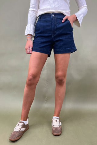 Person wearing blue shorts and white sneakers on a plain background