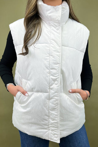 White puffer vest worn by a person on a beige background