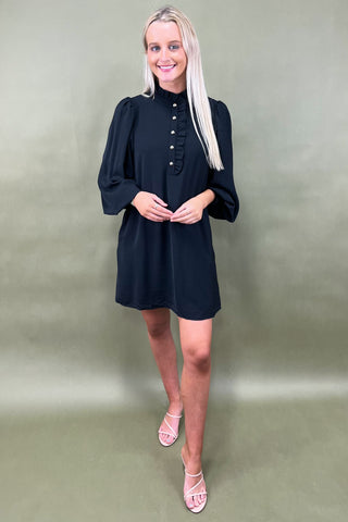 Woman wearing a black dress against a plain background