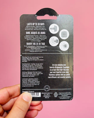 Back of a fragrance packaging with text and branding on a pink background