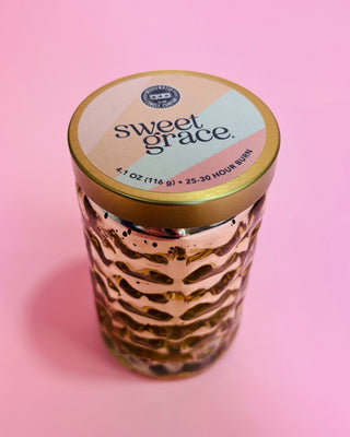 Candle jar with 'sweet grace' label on a pink background