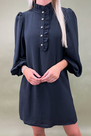 Navy blue dress with ruffled neckline on a plain background