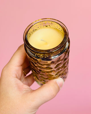 Hand holding a leopard print candle against a pink background