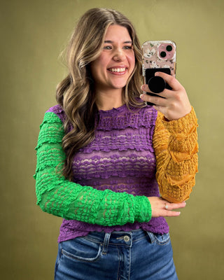 Woman taking a selfie with a colorful sweater on a green background