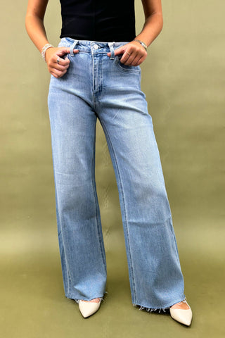Person wearing light blue wide-leg jeans on a green background