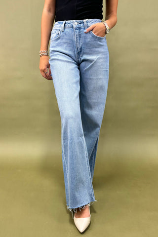 Person wearing light blue jeans on a green background