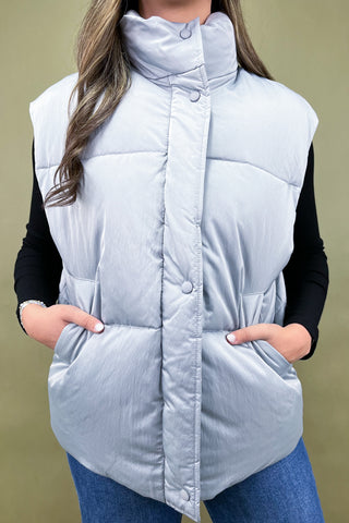 Light gray puffer vest worn by a person on a beige background