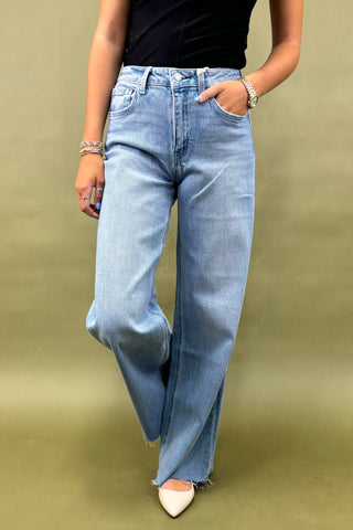 Person wearing light blue flared jeans on a green background