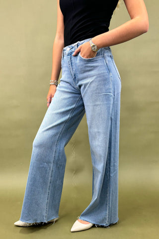 Person wearing blue jeans and a black top on a green background