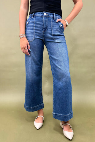 Person wearing blue jeans and white shoes on a beige background