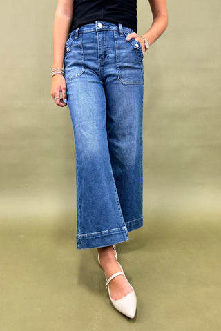 Person wearing blue jeans and white shoes on a green background