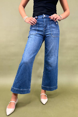 Person wearing blue wide-leg jeans on a beige background