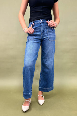 Person wearing blue jeans and a black top on a green background