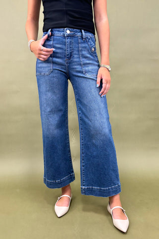 Person wearing blue jeans and a black top on a plain background
