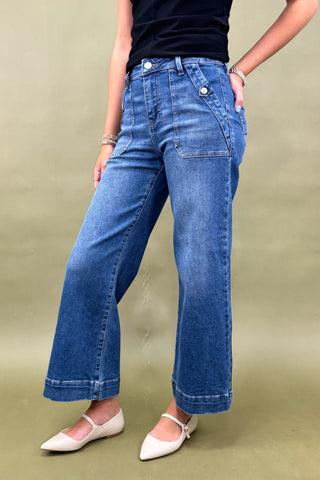 Person wearing blue jeans and a black top on a beige background