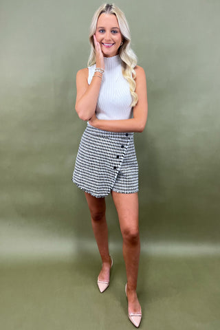 Woman wearing a white top and checkered skirt on a green background