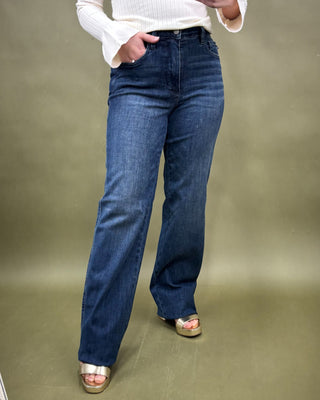 Person wearing blue jeans and a white sweater on a plain background