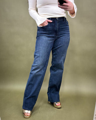 Person wearing blue jeans and a white sweater on a plain background