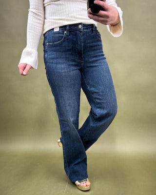 Person wearing blue jeans and a white sweater on a green background