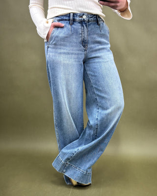 Person wearing light blue wide-leg jeans on a plain background