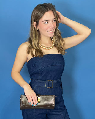 A woman modeling a dark blue denim strapless jumpsuit with wide legs and a matching belt