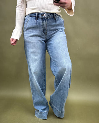 Person wearing blue jeans against a green background