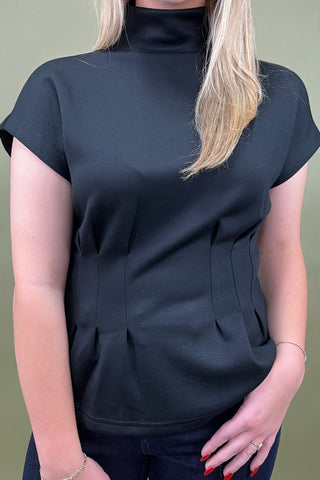 Person wearing a black sleeveless top against a green background