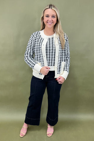 Woman wearing a black and white checkered sweater with a plain background