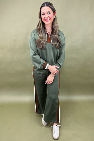 Woman wearing a green tracksuit with white sneakers on a beige background