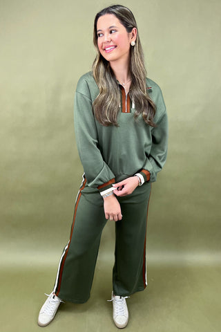 Woman wearing a green tracksuit with white sneakers on a beige background