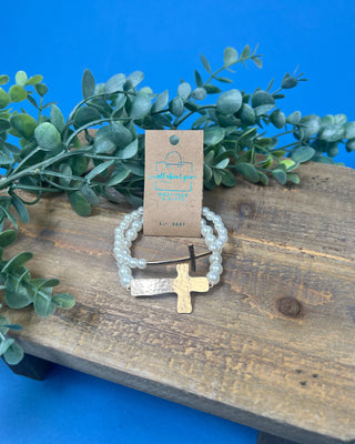 Two-piece gold cross and faux pearl stretch bracelet set featuring hammered and polished gold cross accents on white pearl bead bracelets.