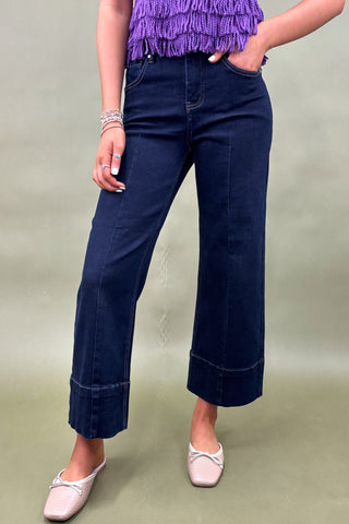 Person wearing navy blue wide-leg jeans with a plain background