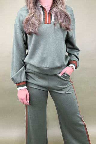 Person wearing a green tracksuit with red accents on a beige background