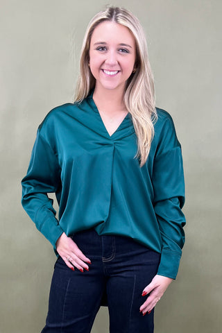 Woman wearing a teal blouse against a plain background
