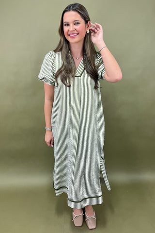Woman wearing a striped dress against an olive green background