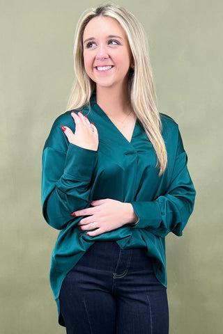 Woman wearing a teal blouse against a green background