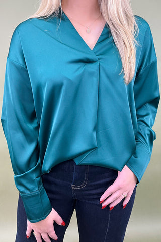 Teal long-sleeve top worn by a person on a plain background