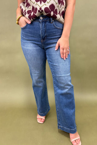 Person wearing blue jeans and a floral top on a green background