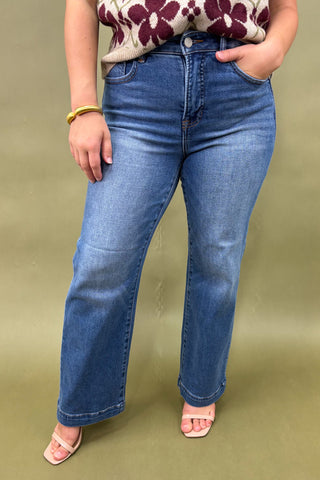Person wearing blue jeans and a floral top on a beige background