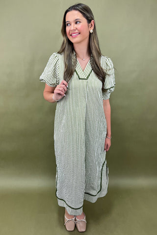 Woman wearing a green and white striped dress against an olive green background