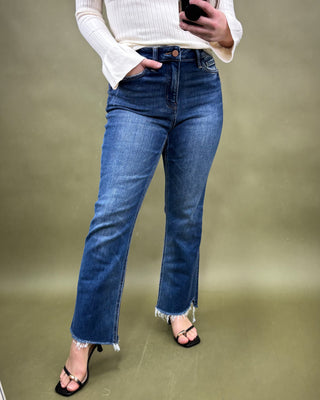 Person wearing blue jeans and a white sweater against a green background