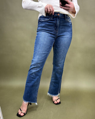 Person wearing blue jeans and a white top on a plain background