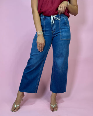 Person wearing blue jeans and a red top on a pink background
